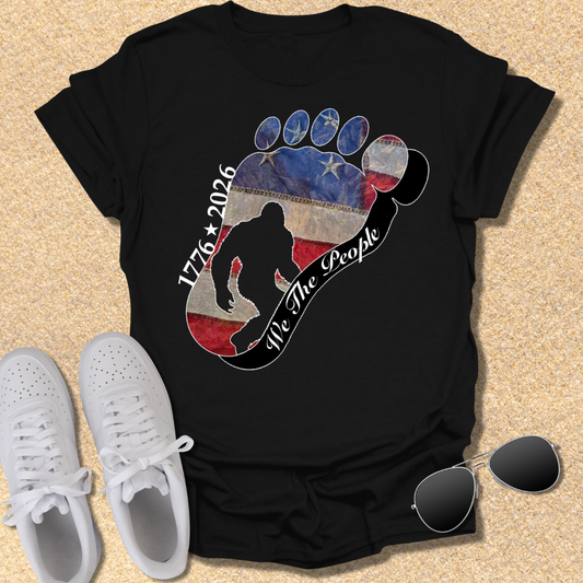 Going Norther Bigfoot T-Shirt — Footprint Silhouette with Distressed Flag & "1776 - 2026 - We The People"
